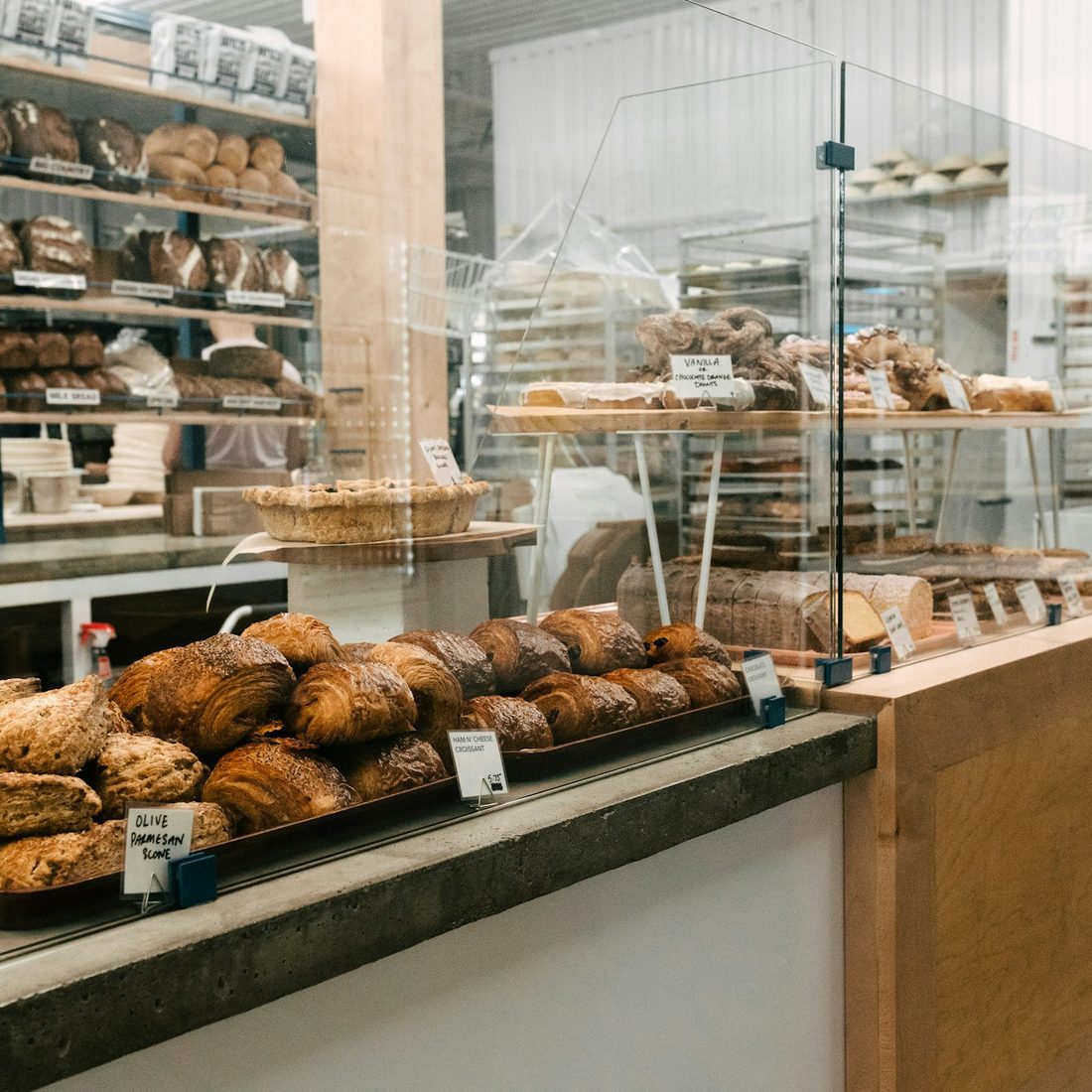 Bakery counter lined with fresh loaves, pastries and buns